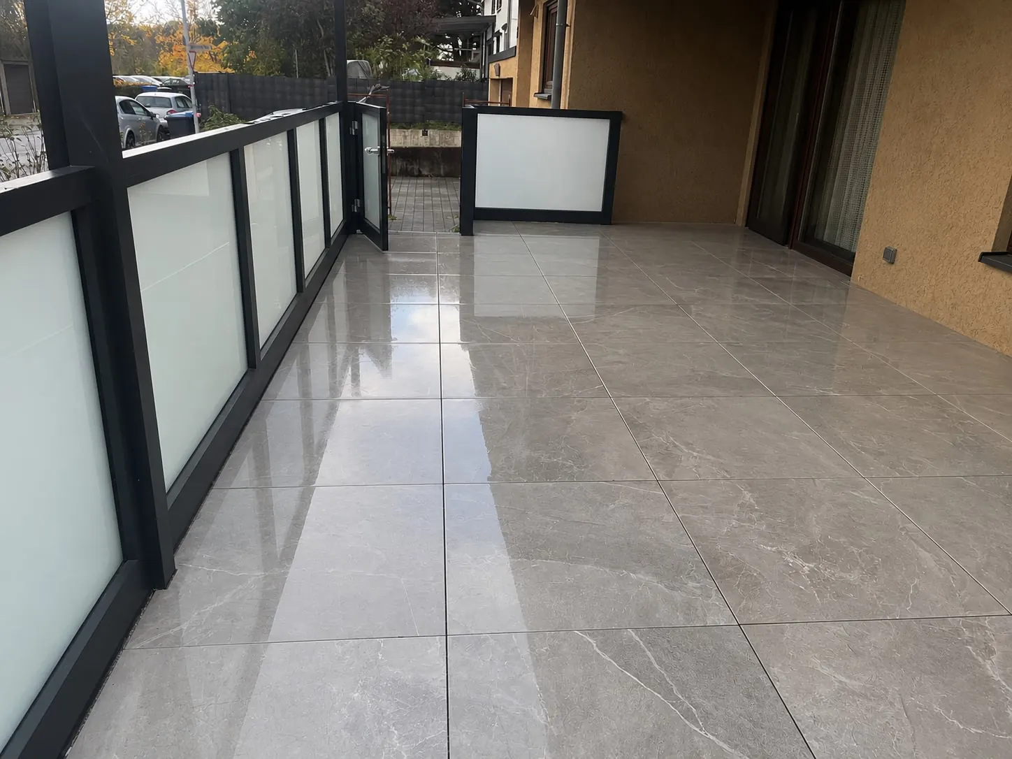 Balkon-Terrasse mit glänzendem Feinsteinzeug in Marmoroptik und Glasgeländer