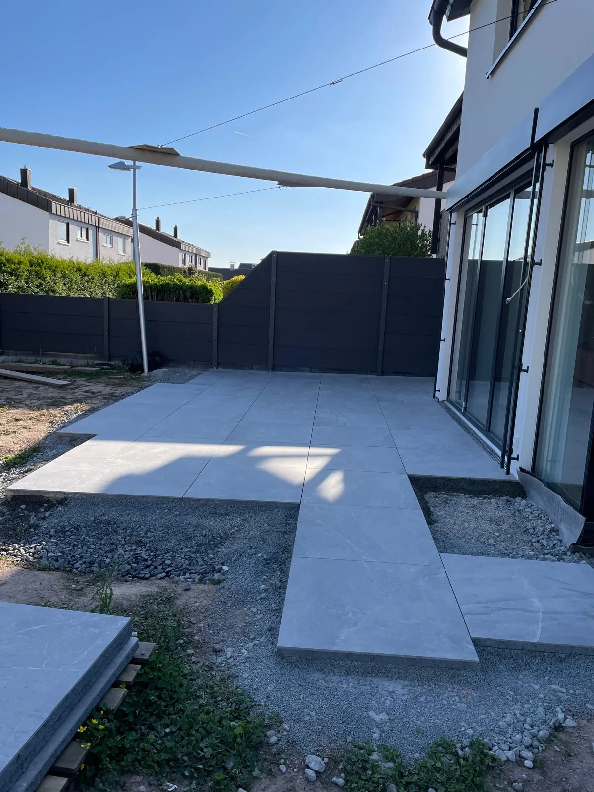 Moderne Terrasse aus großformatigem Feinsteinzeug an einem Neubau