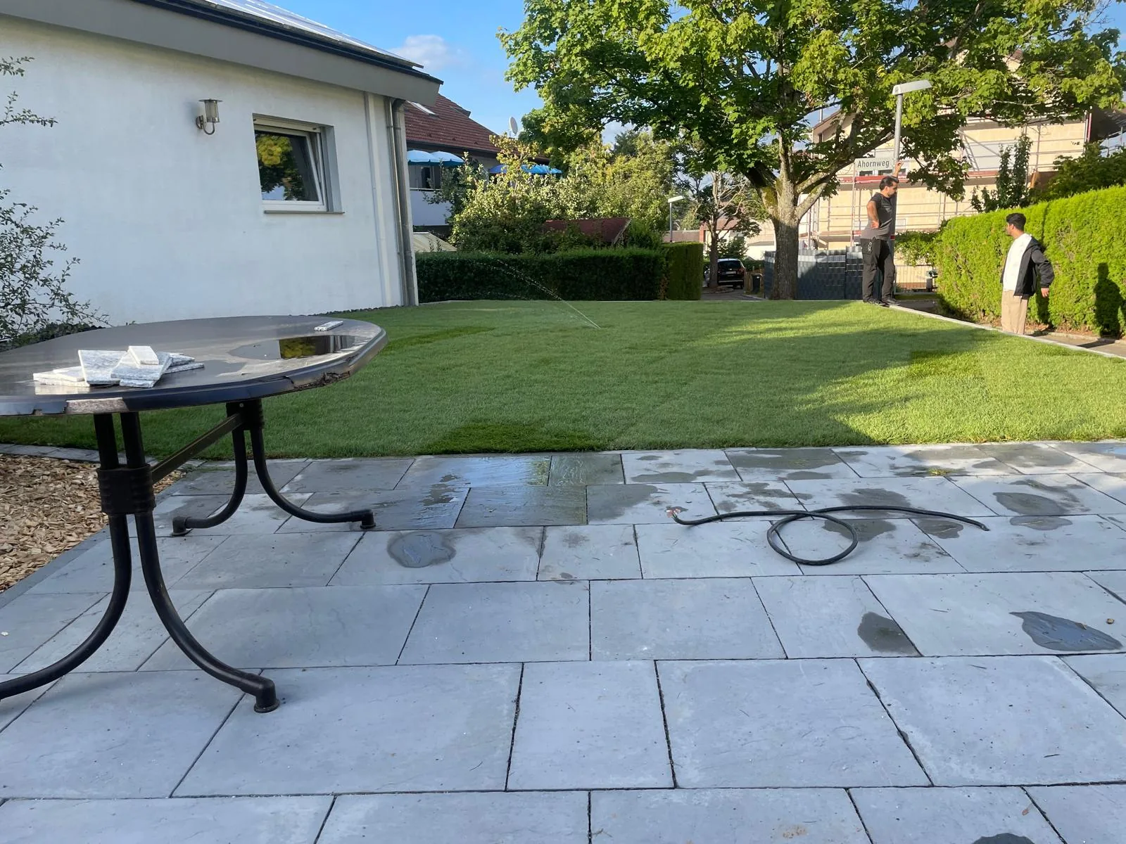 Neue Steinterrasse mit angrenzendem frischem Rasen und Baum