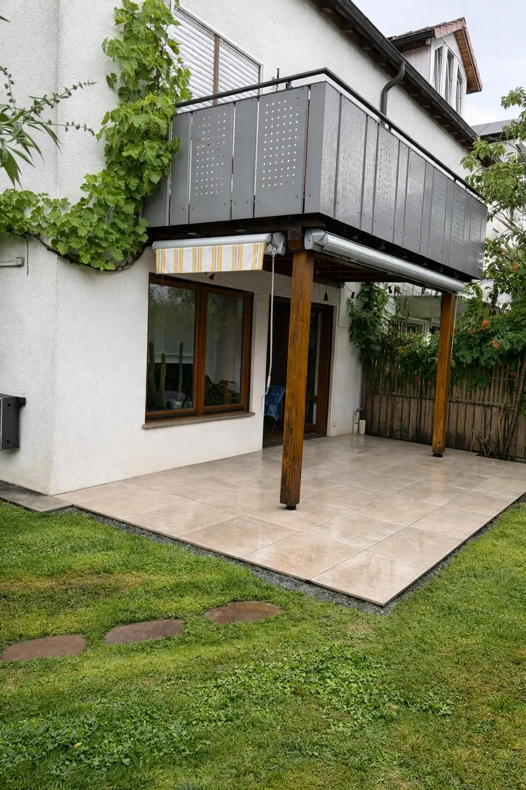 Neue Terrasse mit hellen Platten unter dem Balkon eines Wohnhauses